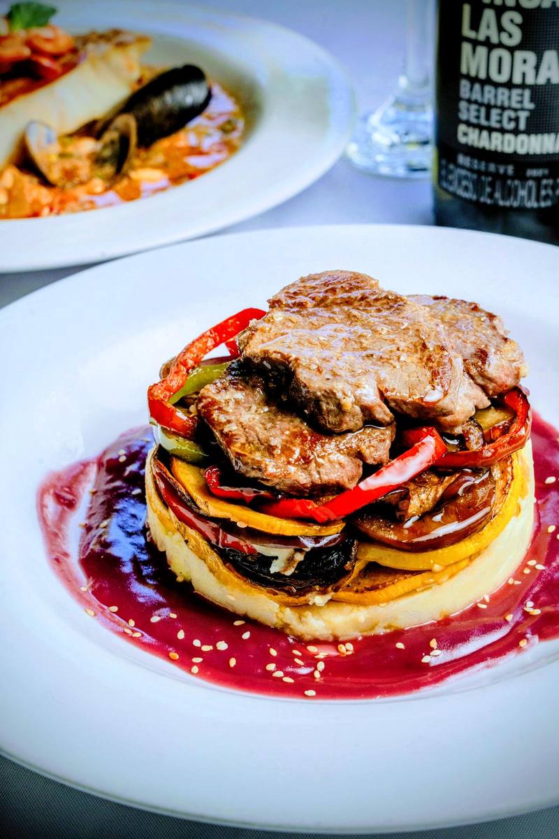 Carne a la parrilla sobre verduras asadas con salsa roja