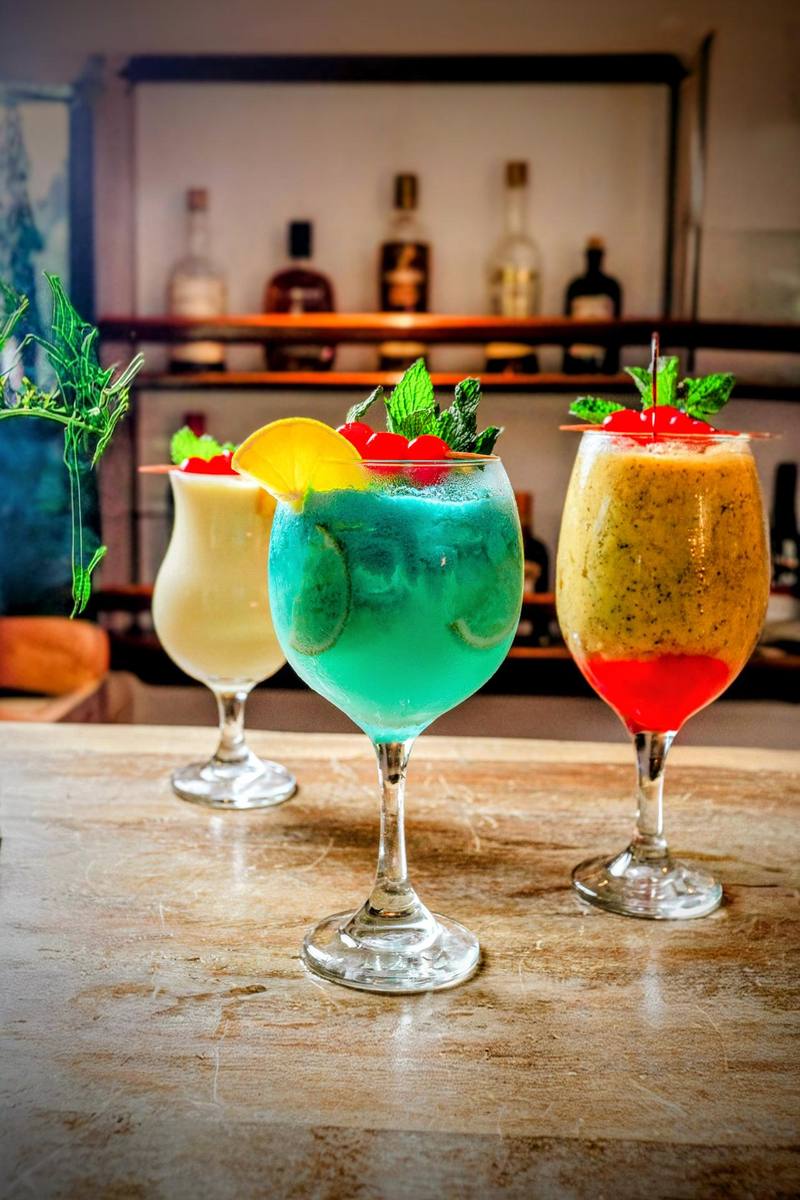 Tres cócteles de autor de colores vivos servidos en la barra