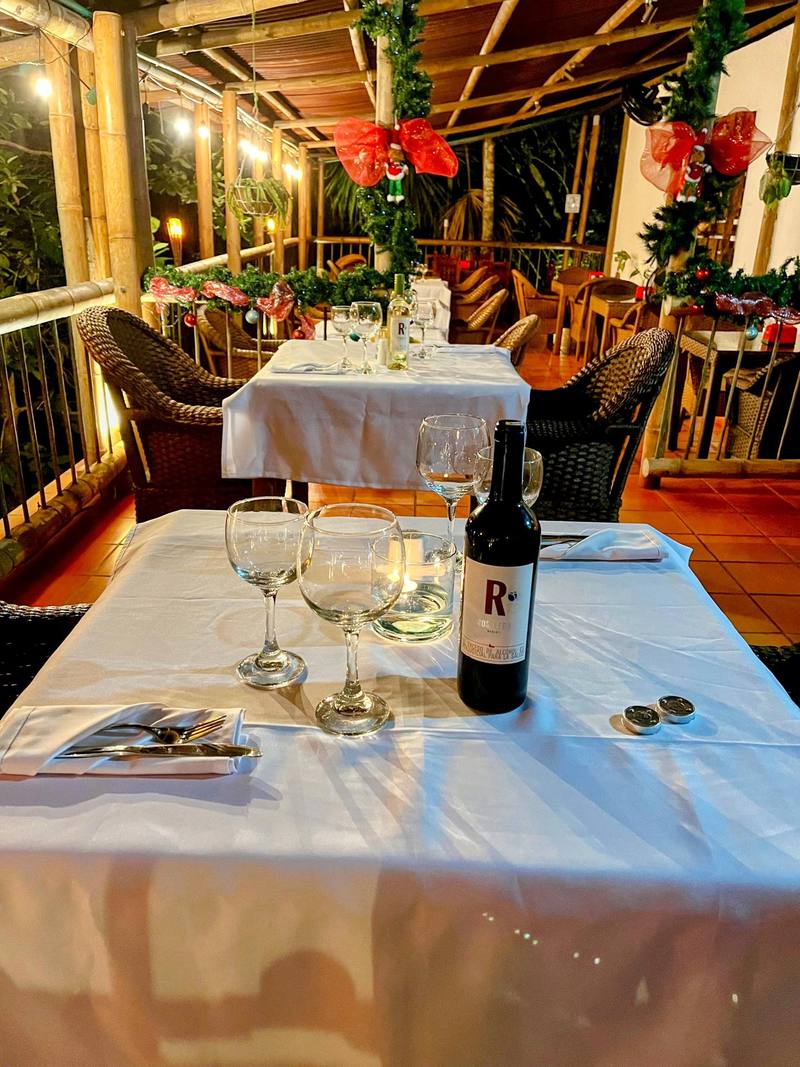 Mesa de la terraza con copas, vino y decoración festiva entre la selva